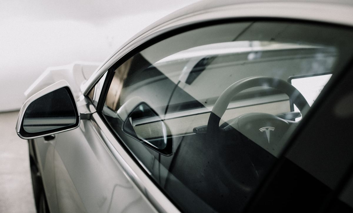 Close-up of a tinted car window and side mirror