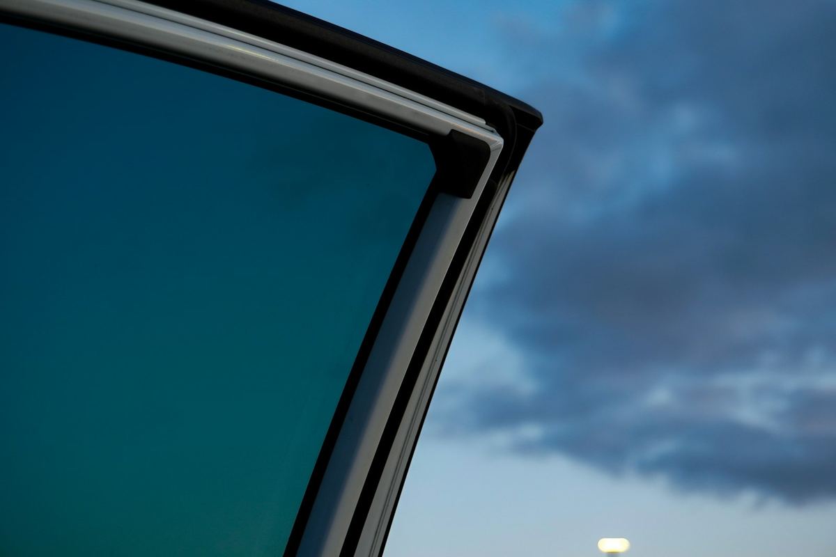 Dark tinted rear quarter glass against an evening sky